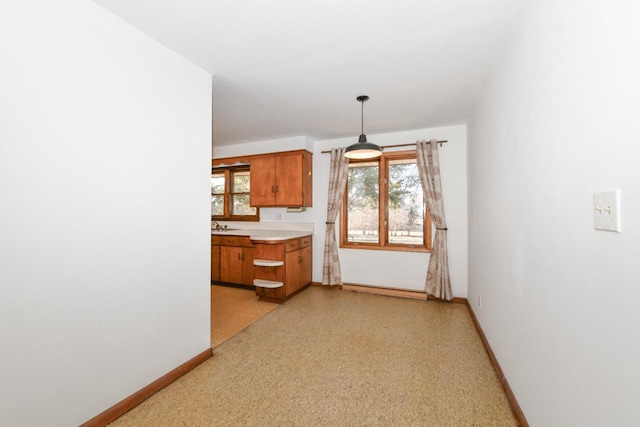 kitchen with baseboards, brown cabinets, hanging light fixtures, and light countertops