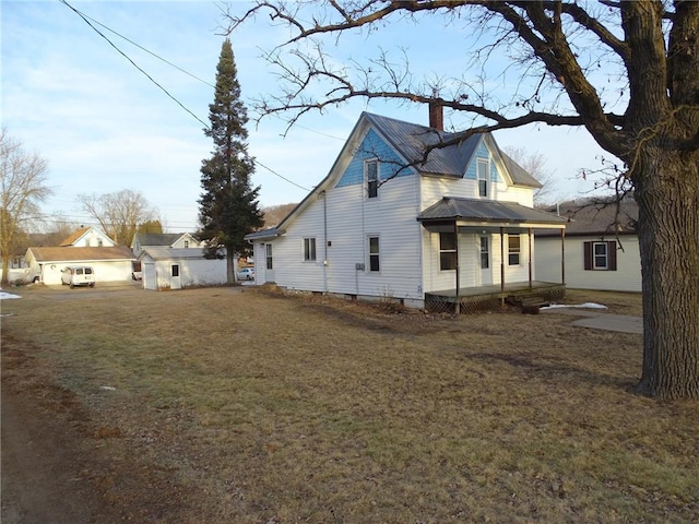 view of property exterior featuring a chimney, a yard, and metal roof