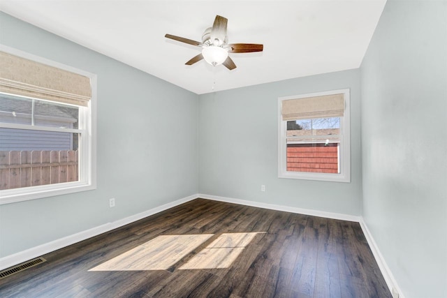 spare room with visible vents, baseboards, dark wood-type flooring, and a ceiling fan