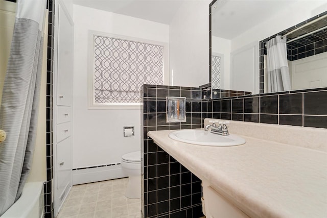 full bathroom with tile patterned floors, toilet, a sink, tile walls, and baseboard heating