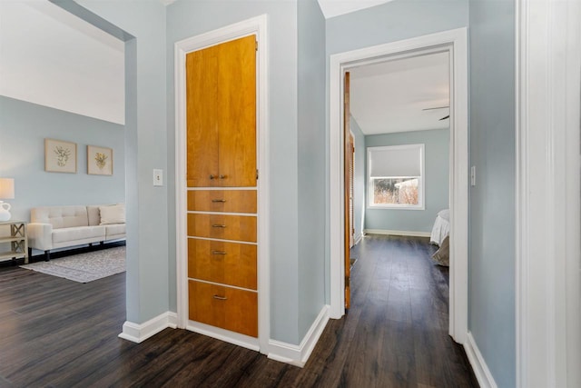 corridor with dark wood-style floors and baseboards