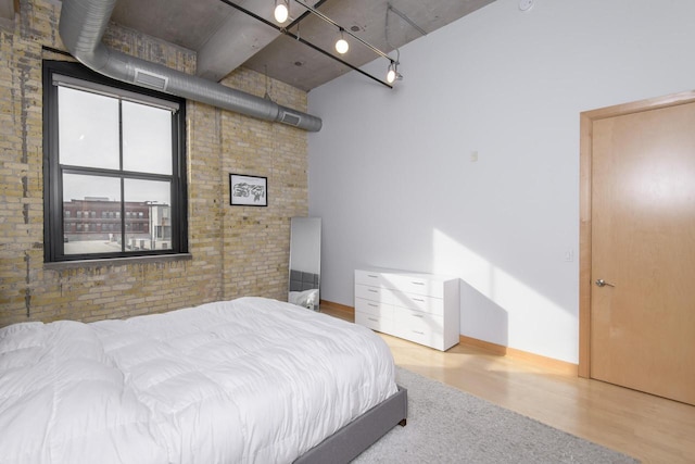 bedroom featuring wood finished floors and brick wall