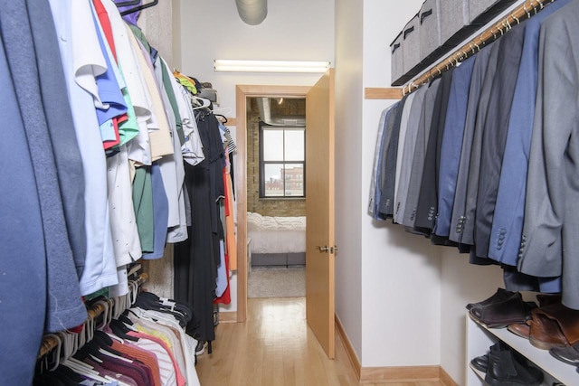 walk in closet with light wood-style floors