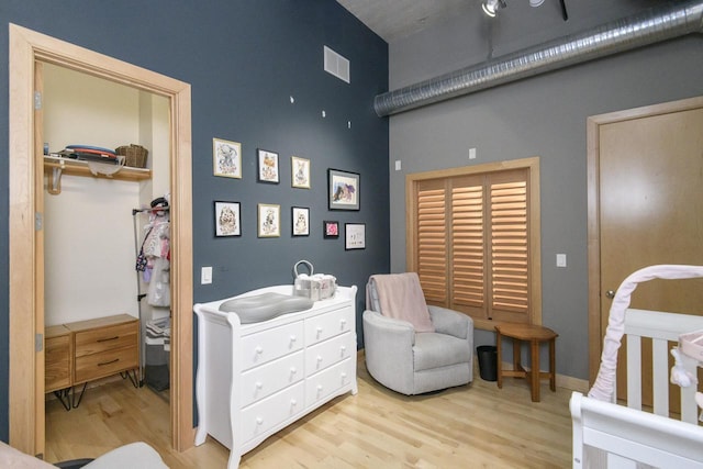 bedroom with visible vents, a high ceiling, and wood finished floors