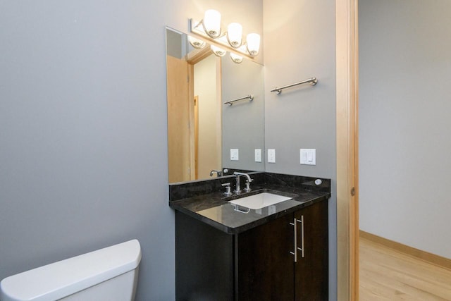 bathroom with toilet, wood finished floors, and vanity