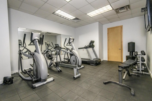 exercise room with visible vents, a paneled ceiling, and baseboards