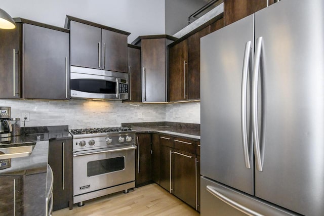 kitchen with light wood-style flooring, backsplash, appliances with stainless steel finishes, and dark brown cabinets