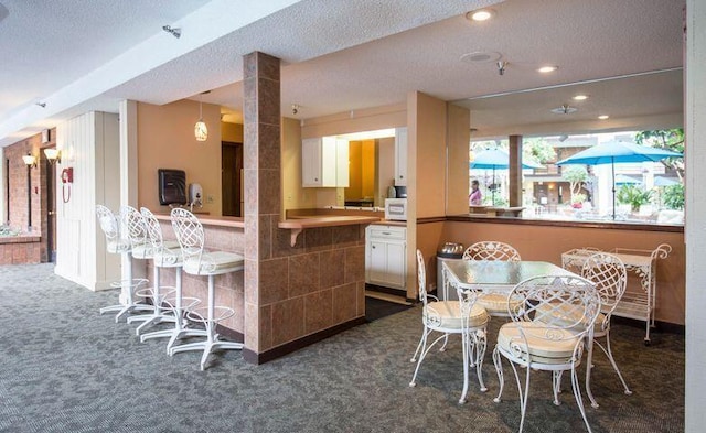 dining area with recessed lighting, dark carpet, a dry bar, and a textured ceiling