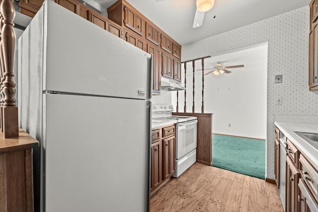 kitchen with under cabinet range hood, white appliances, light countertops, and wallpapered walls