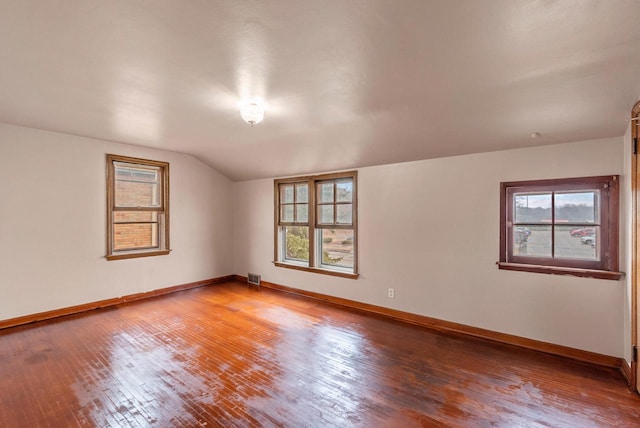 spare room featuring visible vents, hardwood / wood-style floors, baseboards, and vaulted ceiling