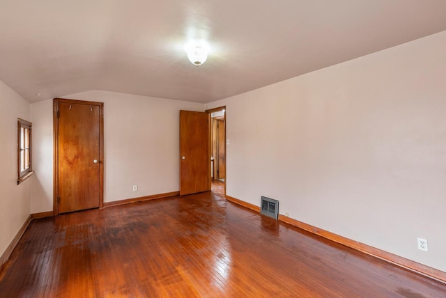 unfurnished room featuring visible vents, wood-type flooring, baseboards, and vaulted ceiling