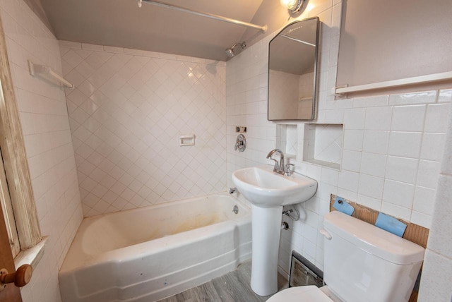 full bath with toilet, washtub / shower combination, tile walls, and wood finished floors