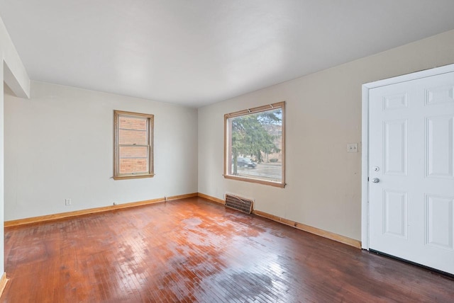 unfurnished room with hardwood / wood-style floors, baseboards, and visible vents