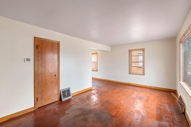 empty room with visible vents, baseboards, and hardwood / wood-style flooring