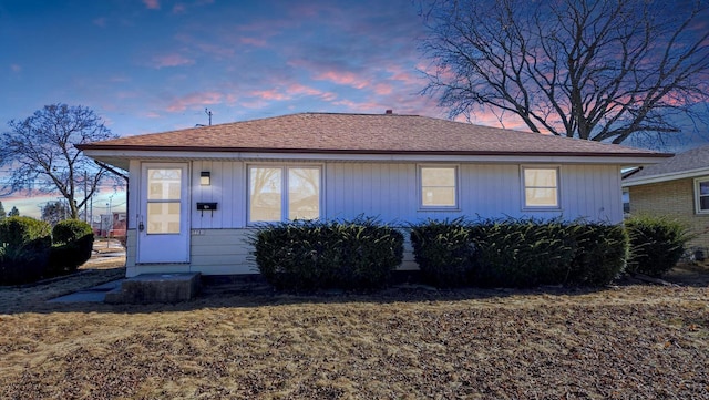 back of property at dusk featuring roof with shingles