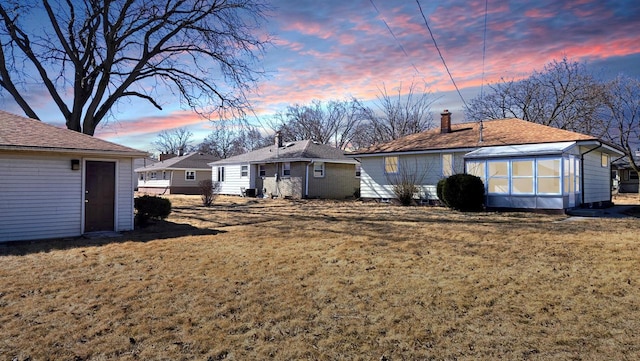 back of house with a chimney, a yard, and an outdoor structure