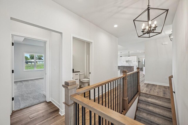 corridor featuring recessed lighting, baseboards, an upstairs landing, and wood finished floors