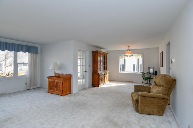 living area featuring baseboards, an inviting chandelier, and carpet floors