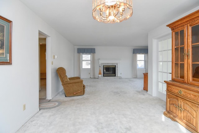 living room featuring light carpet, an inviting chandelier, and a glass covered fireplace