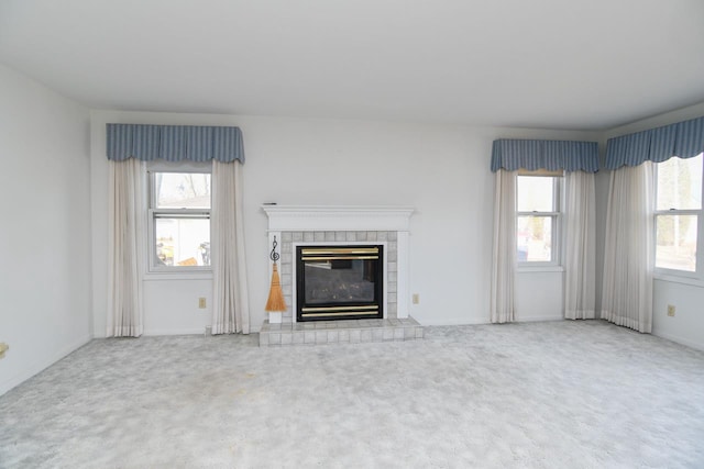 unfurnished living room with a tiled fireplace and carpet flooring