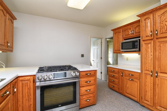 kitchen with light countertops, brown cabinetry, light colored carpet, and stainless steel appliances