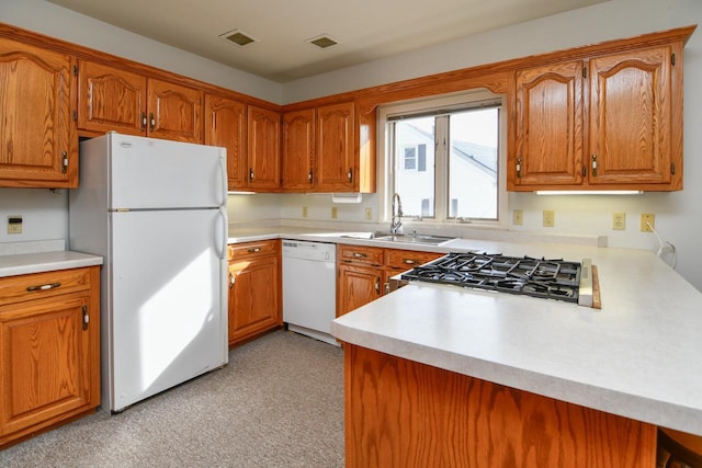 kitchen with visible vents, brown cabinets, white appliances, and a sink