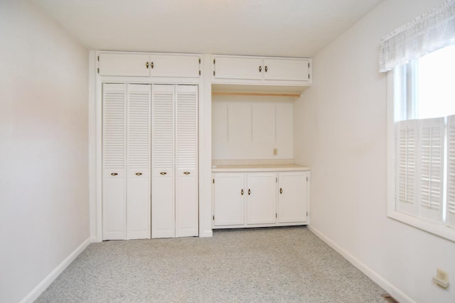 unfurnished bedroom with baseboards, a closet, and light carpet