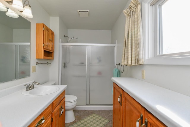 full bathroom featuring vanity, toilet, visible vents, and a stall shower