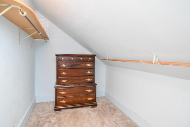 walk in closet with vaulted ceiling and light carpet