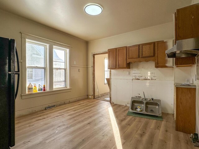 kitchen featuring light wood-type flooring, visible vents, brown cabinetry, and freestanding refrigerator