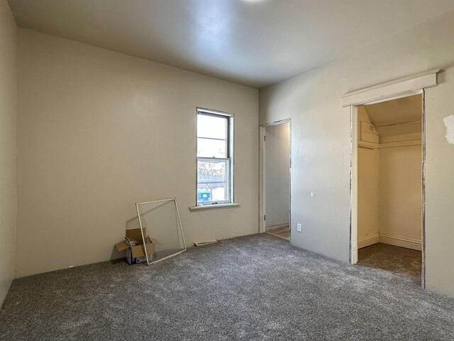 unfurnished bedroom featuring a spacious closet, carpet flooring, and a closet