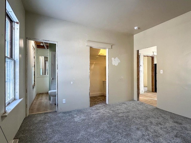 unfurnished bedroom featuring a walk in closet, a closet, and carpet flooring