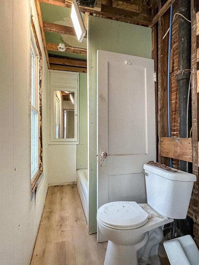 bathroom featuring a bathing tub, toilet, and wood finished floors