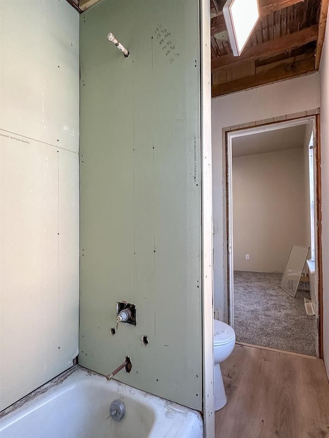 full bath featuring wood finished floors, toilet, and a bathtub