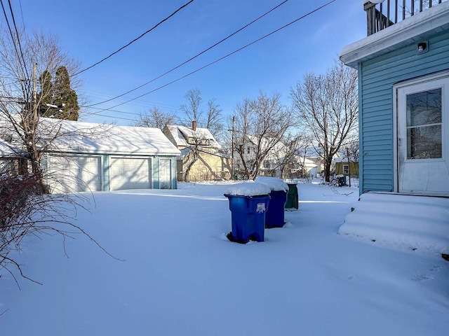 snowy yard featuring a garage and an outdoor structure