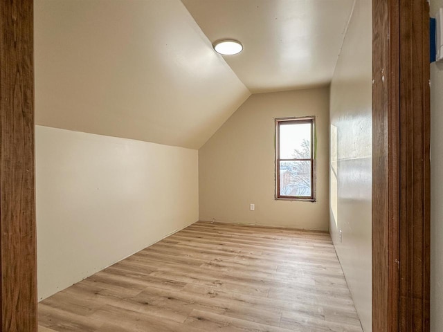 bonus room with light wood-style flooring and vaulted ceiling