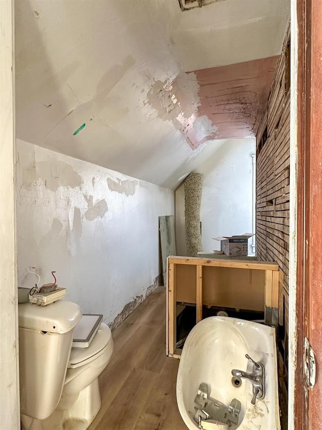 bathroom featuring toilet, lofted ceiling, and wood finished floors