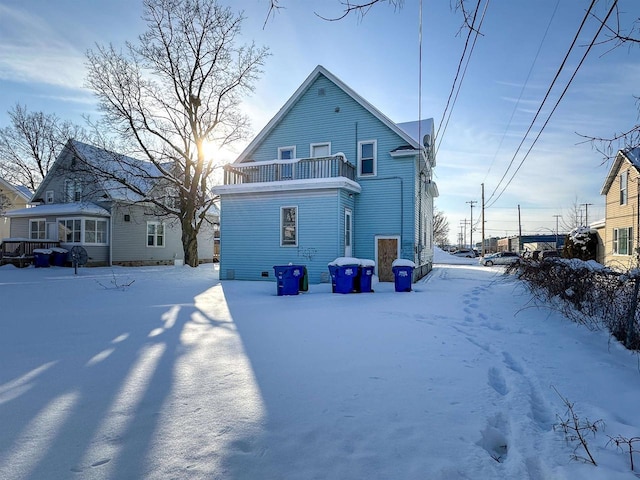 snow covered back of property with a balcony