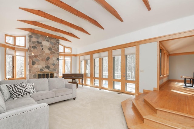 carpeted living area with a wealth of natural light, beam ceiling, a fireplace, and high vaulted ceiling