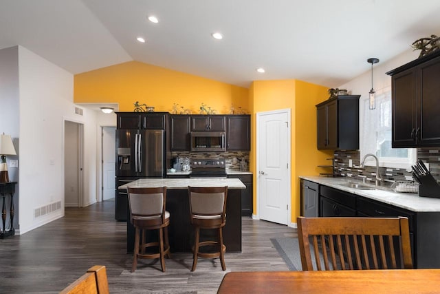 kitchen featuring visible vents, a center island, vaulted ceiling, stainless steel appliances, and a sink