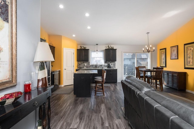 living area featuring dark wood-type flooring, recessed lighting, baseboards, a chandelier, and vaulted ceiling