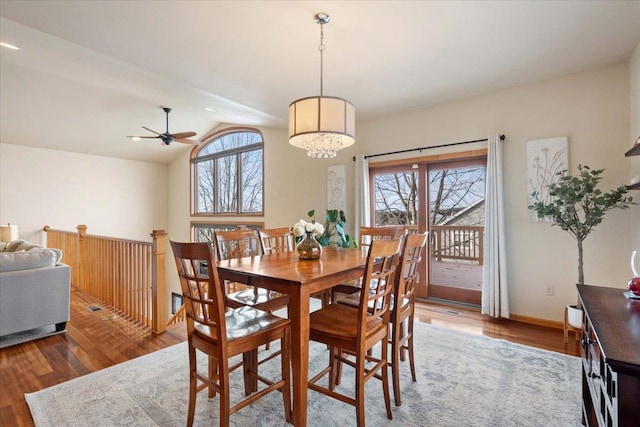 dining room featuring vaulted ceiling, a healthy amount of sunlight, baseboards, and wood finished floors