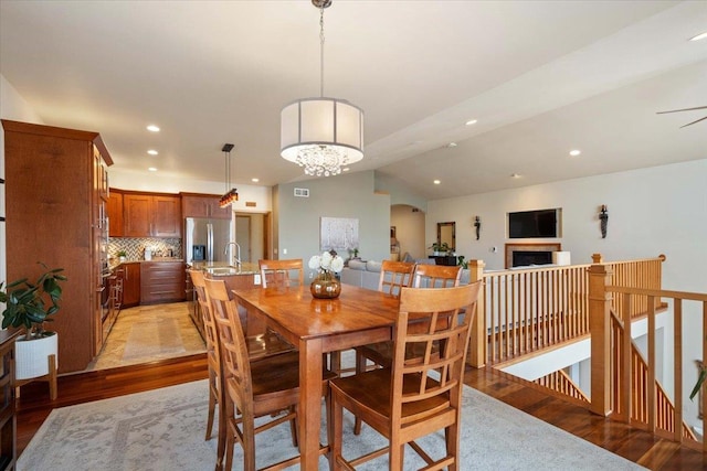 dining room with visible vents, lofted ceiling, a fireplace, recessed lighting, and light wood-style floors