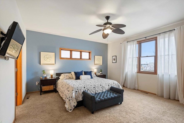 bedroom with visible vents, light colored carpet, baseboards, and ceiling fan