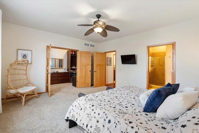 bedroom featuring a ceiling fan, visible vents, baseboards, ensuite bathroom, and light colored carpet