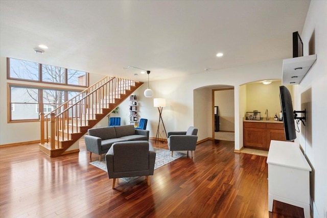 living area with stairs, hardwood / wood-style flooring, baseboards, and arched walkways