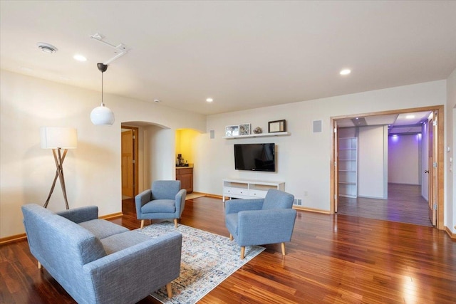 living area with visible vents, wood finished floors, and arched walkways