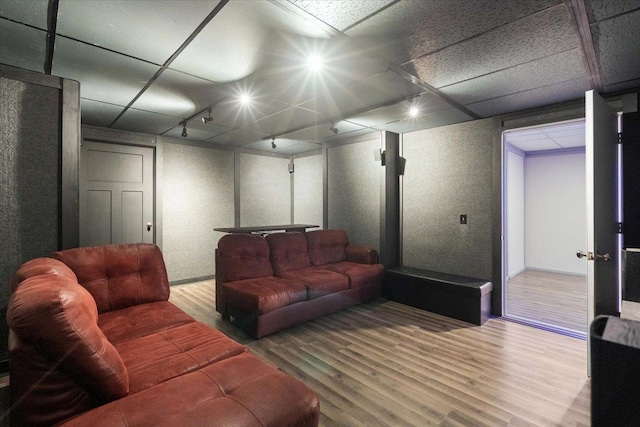 living area with a paneled ceiling, wood finished floors, and track lighting