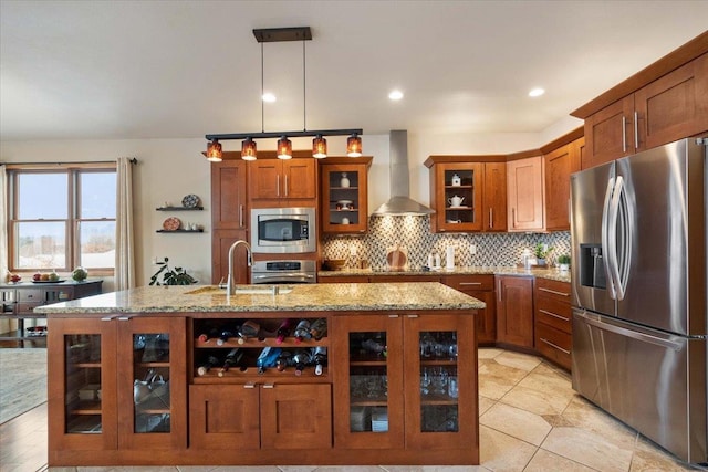 kitchen with wall chimney exhaust hood, brown cabinetry, appliances with stainless steel finishes, and a sink