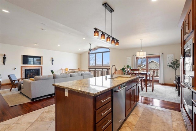 kitchen with a sink, plenty of natural light, appliances with stainless steel finishes, and a glass covered fireplace